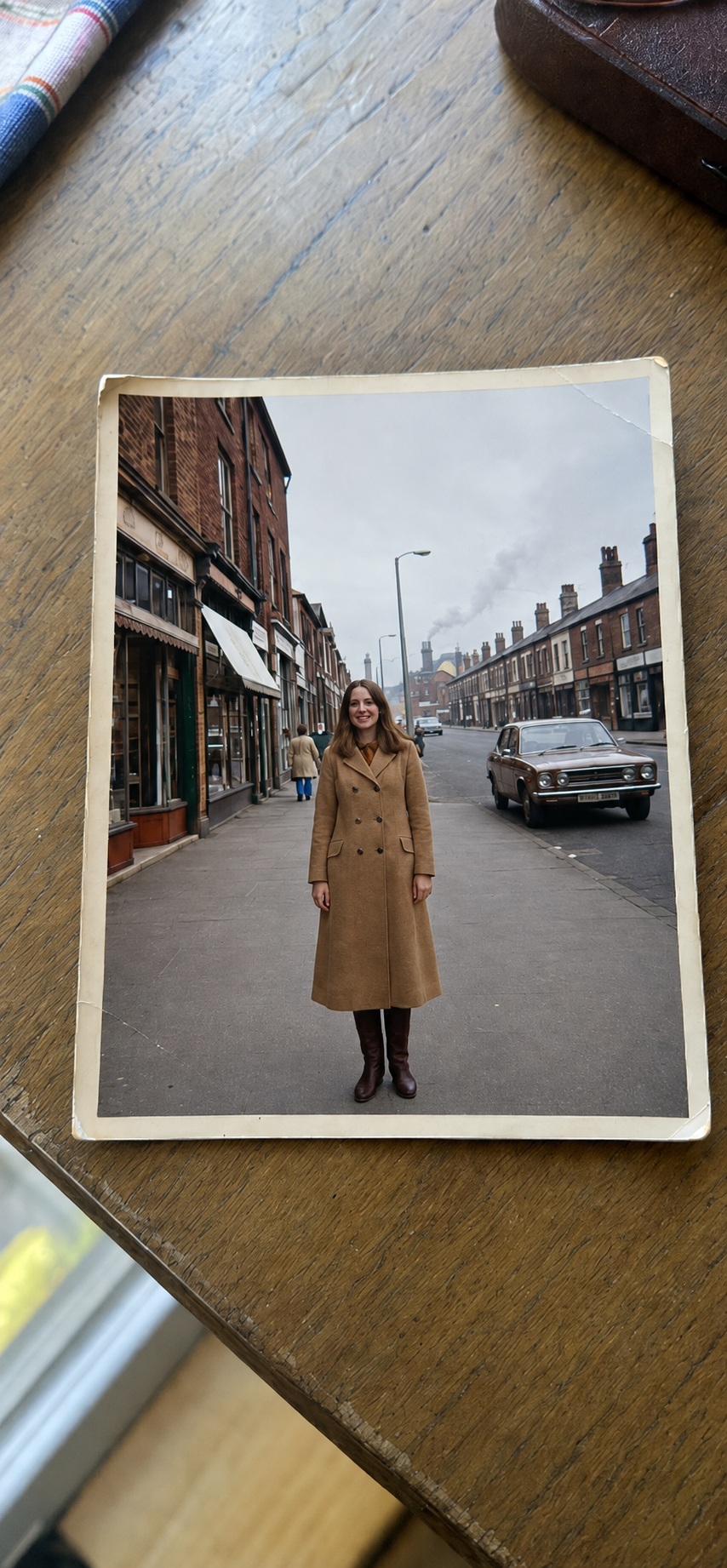 A faded 1970s photograph of a woman on a Northern English street, lying on a kitchen table